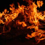 Close-up of a blazing bonfire with intense flames against a dark background.