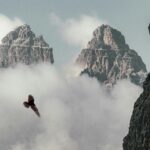 Breathtaking view of the Dolomites with a bird soaring through misty clouds, creating a dramatic natural scene.