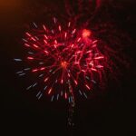 Colorful fireworks display with red and blue sparks in the night sky.